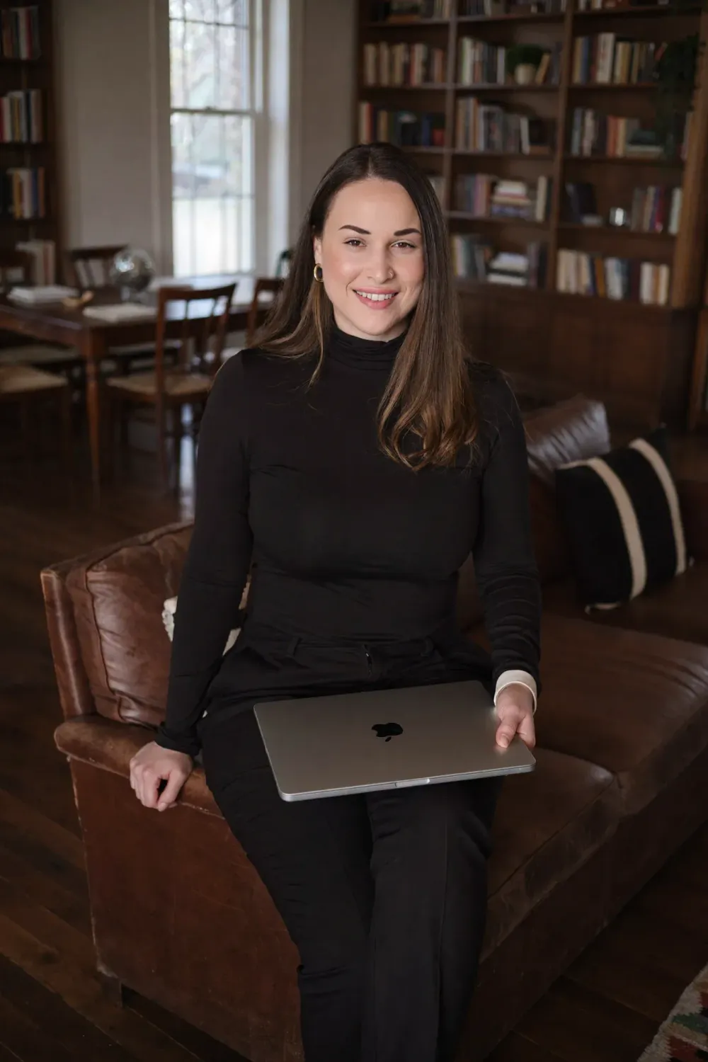 Yasmine Moura, fondatrice d’Euphoriste, assise dans une bibliothèque avec son ordinateur portable